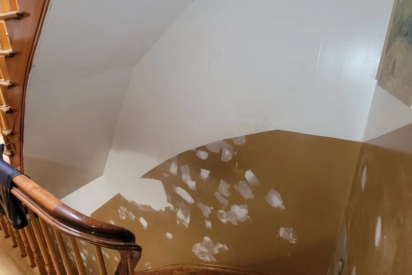 The same stair hall before painting: a brown wall covered in white plaster patches.
